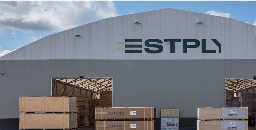 The image shows a large, white warehouse building with a blue roof, a double door, and stacks of wooden boxes inside.

AI-generated content may be incorrect.